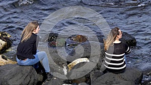 Two girls sit on the rocks at the Causeway Coast in Northern Ireland