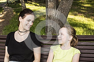 Two girls are sitting on a bench talking and laughing