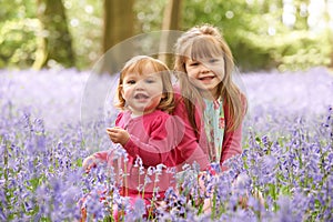Two Girls Sitting In Bluebell Woods Together