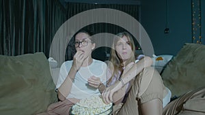 Two girls sitting on a cozy sofa at home and watching TV