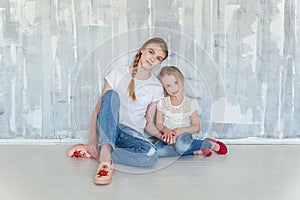 Two girls sitting at the gray wall