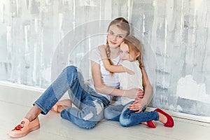 Two girls sitting at the gray wall