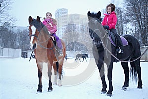 Two girls sitting on horseback at equestrian photo