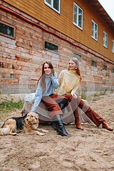 Two girls sitting next to each other. One girl petting a dog