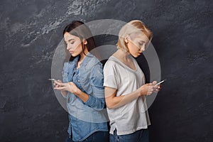 Two girls with smartphones looking in smartphones