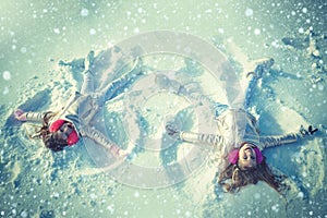 Two Girls on a snow angel shows. Children playing and making a snow angel in the snow. Top view.