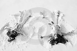 Two Girls on a snow angel shows. Smiling children lying on snow with copy space. Children playing and making a snow