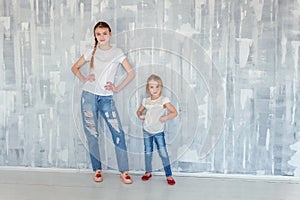 Two girls standing at the gray wall