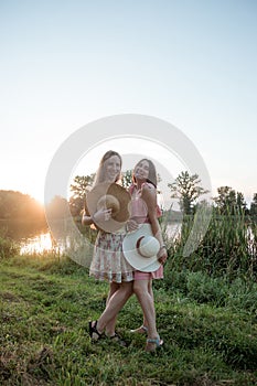 Two girls standing near the lake at sunset