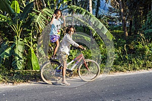 Two girls strike a pose with their bicycle