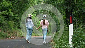 Two girls stroll along the hiking trails in the Alps. Road signaling posts. Mother and daughter having a joyful time