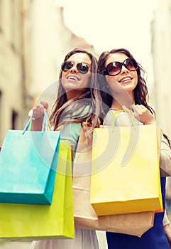 Two girls in sunglasses with shopping bags in ctiy