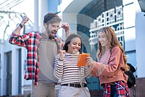 Two girls with tablet and guy rejoicing in the street