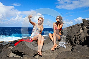 two girls taking photo on the beach in summer holidays and vacation