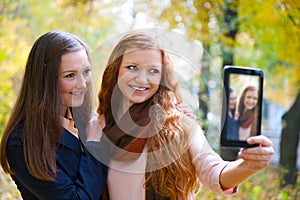 Two girls taking picture with digital tablet
