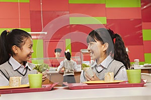 Two girls talking at lunch in school cafeteria