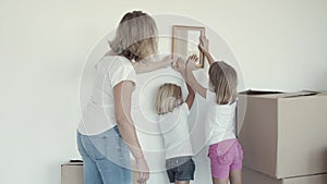 Two girls and their mom choosing place on wall for picture