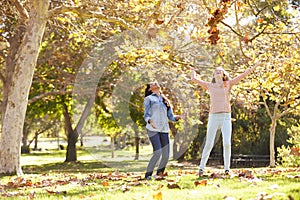 Two Girls Throwing Autumn Leaves In The Air