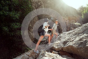 Two girls of a tourist`s girlfriend climb the mountains, help each other, reach out a helping hand.