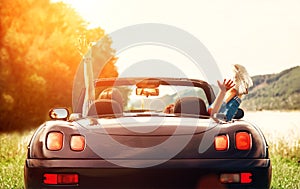 Two girls travelers sit in cabriolet car and enjoy with beautiful view