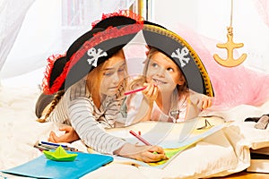 Two girls in tricorns drawing the treasure map