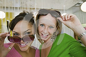 Two Girls Trying on Sunglasses in Boutique portrait close up