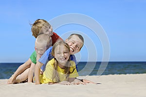 Two girls and two boys in colorful t-shirts playing on a sandy beach