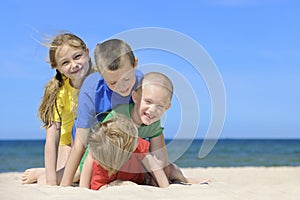 Two girls and two boys in colorful t-shirts playing on a sandy beach