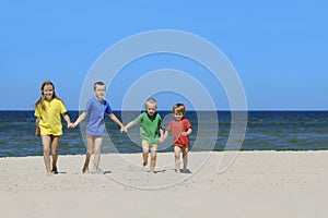 Two girls and two boys in colorful t-shirts walking on a sandy beach