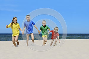 Two girls and two boys in colorful t-shirts walking on a sandy beach