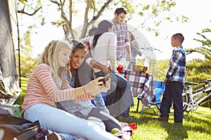 Two Girls Using Mobile Phone On Family Camping Holiday