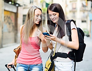 Two girls using smartphone navigating system