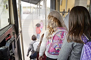 Two girls waiting behind their friends to get off school bus