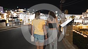 Two girls walk through the tourist town of Pefkos