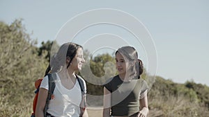 Two girls walking along dirt road, enjoying hiking adventure.