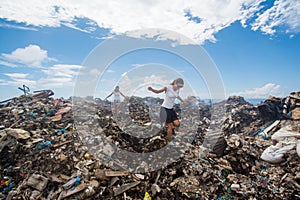 Two girls walking among trash at garbage dump