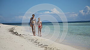 Two girls walking on a tropical beach