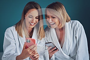 Two girls wearing bathrobe in spa or hotel having fun