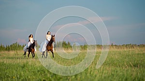 Two girls in white dresses on horseback. Girls jumping on the field on horseback. Slow motion.