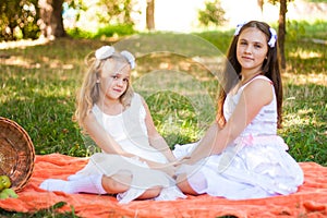 Two Girls in White Dresses Play On Orange Picnic Blanket