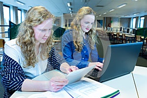 Two girls working on computer and tablet in computer classroom