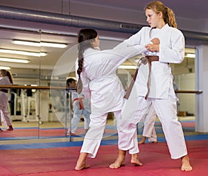 Two girls working in pair mastering new karate moves during group class with coach