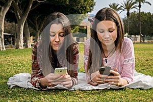 Two girls write in mobile phones