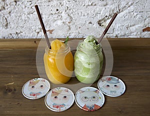 Two glasees of fresh mango and kiwi smoothie on a wooden table