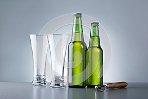 Two Glass And Bottles Of Beer Against Grey Background.