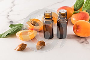 two glass bottles with a dropper with apricot organic oil on the background of ripe fruits. antioxidant care
