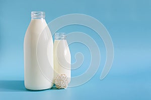 Two glass bottles of milk on a bright blue background. One liter and 0.5 liters of milk in glass bottles on