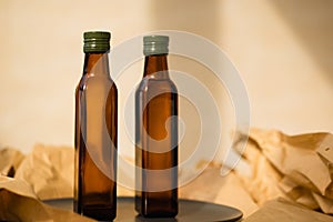 Two glass brown transparent faceted bottles without labels empty and full with vegetable oil with green metal caps