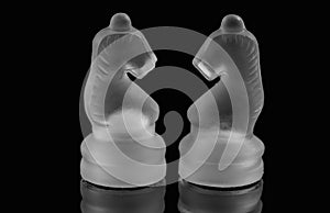 Two glass chess pieces on a black background