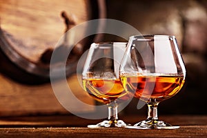 Two glass of Cognac and old oak barrel defocussed